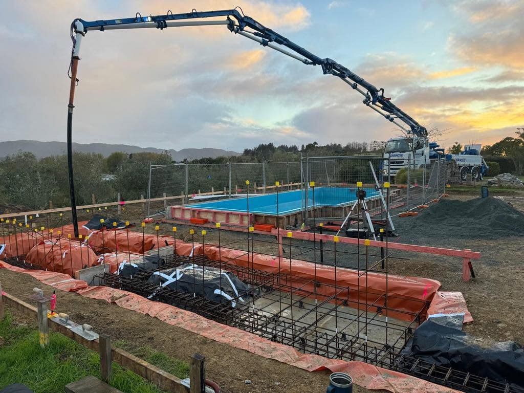 Concrete pump truck pouring foundations at dusk